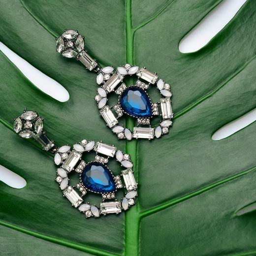 Vivaha blue-stone drop earrings photographed on a leaf